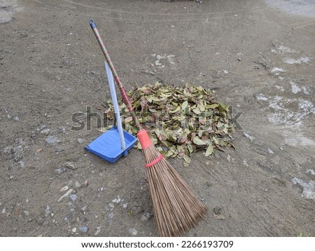 wooden broom and dustpan on ground, with scraps or litter