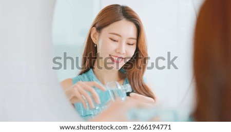 Oral hygiene concept - asian woman looking in mirror is pouring mouthwash from bottle into mouth before going to work and she feel refreshing Royalty-Free Stock Photo #2266194771