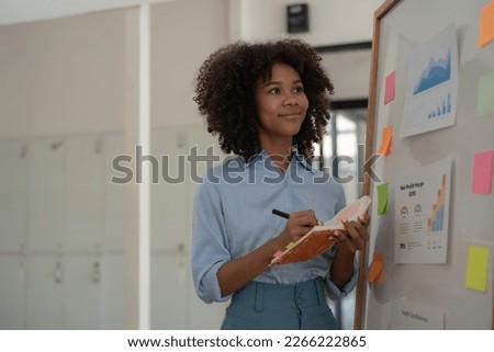 Young creative ethnic businesswoman working on a sticky note on board, planning and analyzing business finance and marketing at the office.