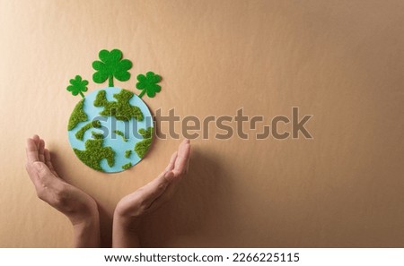 Hands holding paper earth with grass on brown background. World environment day, earth day and save earth concept. Royalty-Free Stock Photo #2266225115