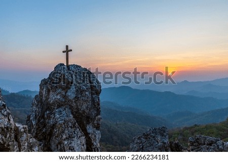 Silhouettes of crucifix symbol on top rock mountain with colorful sunset view background