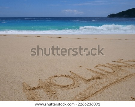 Closeup of word holidays written on the sand on beach and blue summer sky. Panoramic beach landscape. Empty tropical beach and seascape. Orange and golden sunset sky.