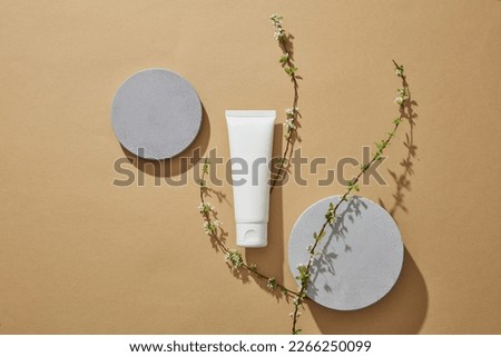 Empty podium or pedestal display on light brown background with cylinder concept. White tube with empty label to promote cosmetic product