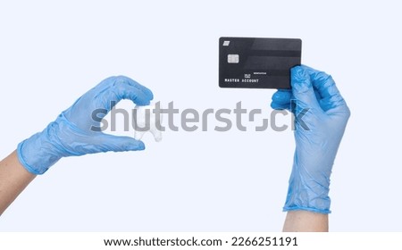 Female dentist hand in blue gloves holds dentist Tooth model and credit card. Light background. Concept of Cost of dental treatment