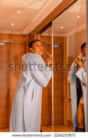 Rich black ethnic woman in hotel room, luxury concept, checking her makeup in the mirror