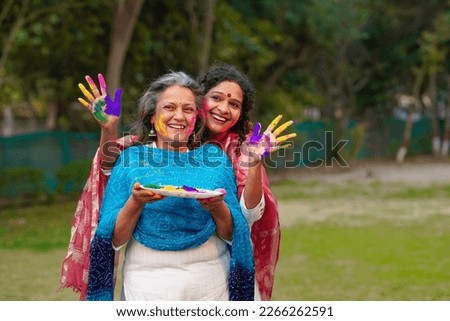 Two Indian woman playing colors at park and celebrating holi festival. Royalty-Free Stock Photo #2266262591