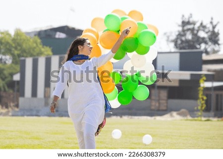 Beautiful happy young indian girl wearing traditional white kurta dress running with tricolor balloons at park celebrating independence day or republic day concept. Royalty-Free Stock Photo #2266308379