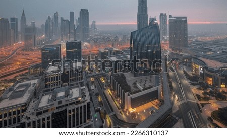 Futuristic Dubai Downtown and finansial district skyline aerial night to day transition timelapse. Many illuminated towers and skyscrapers with morning fog before sunrise