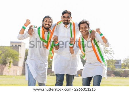 Group of cheering young fans men wearing traditional white kurta and tricolor duppata with face painted cheering for indian cricket, hockey or football team.