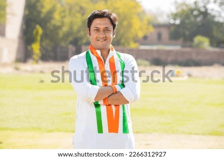 Portrait of young indian man wearing traditional white kurta and tricolor duppata standing cross arms at park. Election and politics, celebrating Independence day or Republic day. Royalty-Free Stock Photo #2266312927