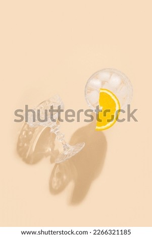Glass with a cocktail with an orange slice on a beige background. Top view, flat lay.