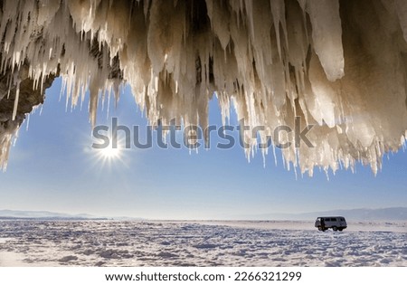 Frozen Baikal Lake. In winter, coastal cliffs of Olkhon Island are covered with unusual crust of ice splashes with long icicles. Tourists come by car on ice Small Sea to take pictures of ice grottoes