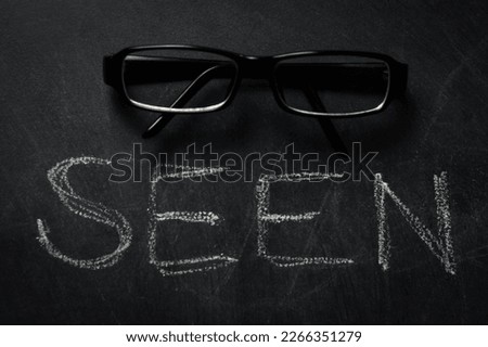 seen - word seen written in chalk on a blackboard with a pair of glasses on it - concept about the vision and visibility of a person, a product...