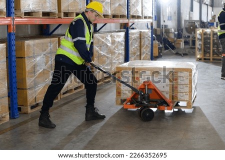Worker in auto parts warehouse use a handcart to work to bring the box of auto parts into the storage shelf of the warehouse waiting for delivery to the car assembly line Royalty-Free Stock Photo #2266352695