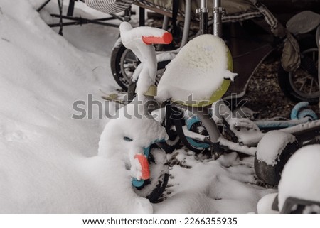 Snow covered toys for children - a bicycle and a scooter