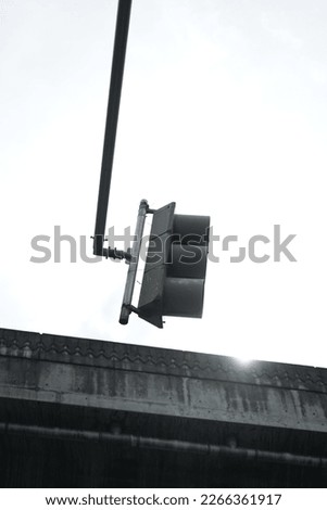 the traffic sign is seen from the side with a little sunlight peeking from the bridge