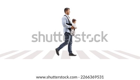 Full length profile shot of a father with a baby in a carrier crossing over pedestrian zebra sign isolated on white background