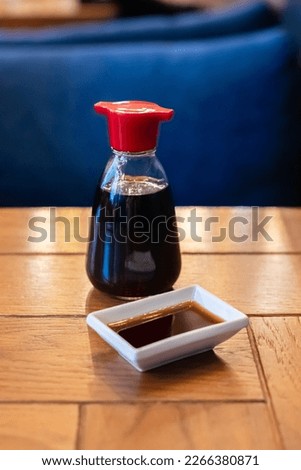 Soy sauce bottle, sauceboat bowl dish of soy sauce on wooden table, selective focus, vertical photo. Royalty-Free Stock Photo #2266380871