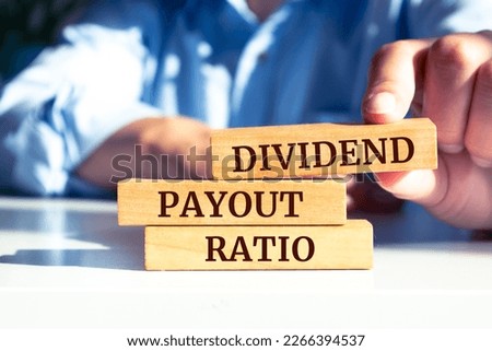 Close up on businessman holding a wooden block with "DIVIDEND PAYOUT RATIO" message