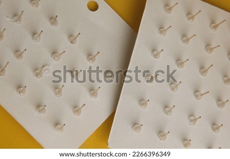 The back of earring. Earring stopper with clear small plastic material. Cheap earring set photo isolated on yellow background.