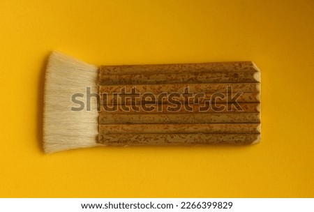 Wooden or bamboo textured handle white brush for cleaning or writing with unusual shape. Object photo isolated on yellow background.