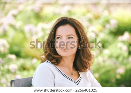 Outdoor portrait of beautiful 40 - 45 years old woman sitting on bench ib green park, healthy lifestyle Royalty-Free Stock Photo #2266401325