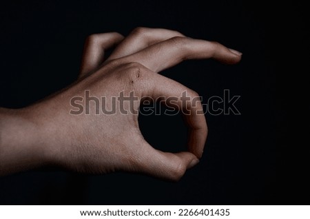hand making ok sign in front of black background
