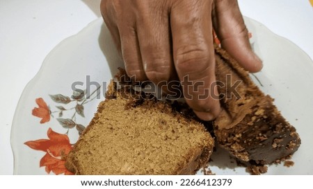 Photo of hand holding delicious chocolate sponge cake on white background