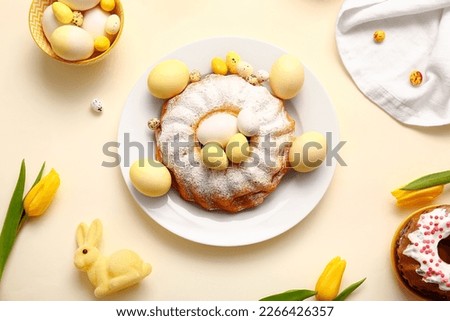 Composition with tasty Easter cake, painted eggs and tulip flowers on color background Royalty-Free Stock Photo #2266426357
