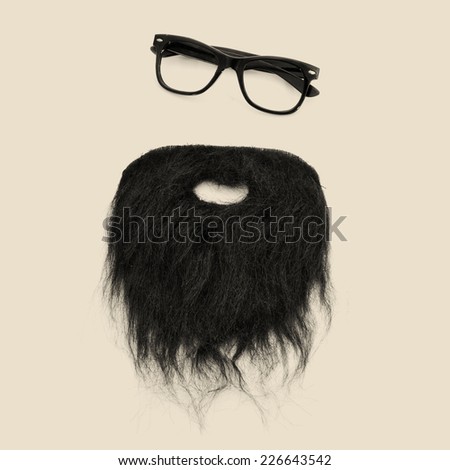 a pair of retro eyeglasses and a beard forming a man face on a beige background