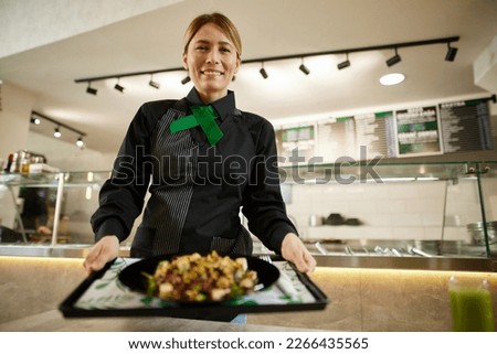 Pretty barmaid holding plate of salad 