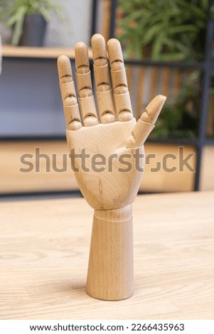 Wooden model of a human hand on a desk. model of a human hand demonstrates open palm
