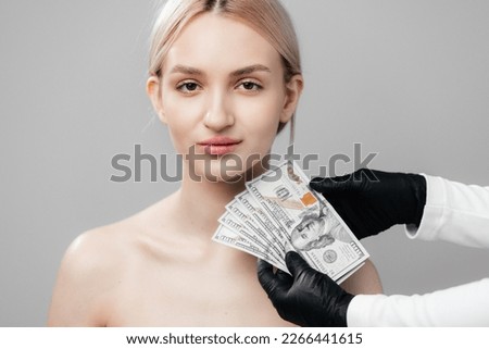 against the background of a pretty young girl, a cosmetologist shows banknotes of money. The concept of financial investment in human beauty