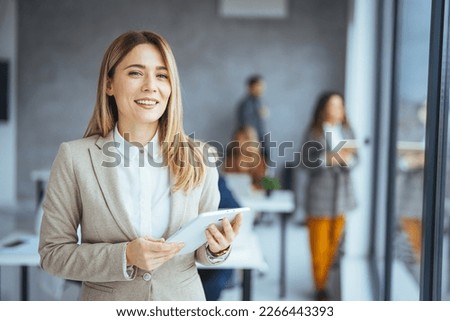 Businesswoman holding a digital tablet while standing in the boardroom. Portrait of a successful business woman using digital tablet. Young attractive female manager working on digital tablet