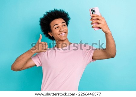 Photo of cheerful optimistic positive blogger millennial man thumbs up cool vibe hold phone selfie portrait isolated on aquamarine color background