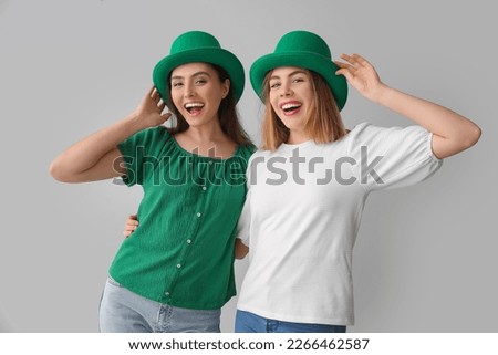Happy young women in hats on light background. St. Patrick's Day celebration