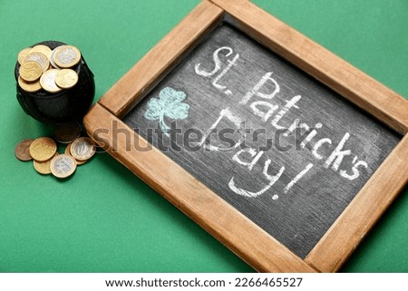 Chalkboard with text ST. PATRICK'S DAY and pot of coins on green background, closeup