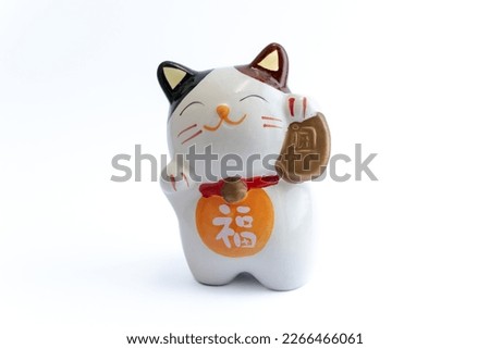 A Maneki-neko or also known as fortune cat in porcelain. Symbolizing luck and wealth, on a white isolated background. Chinese character translate as "blessing". Royalty-Free Stock Photo #2266466061