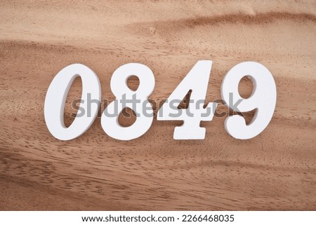 White number 0849 on a brown and light brown wooden background.