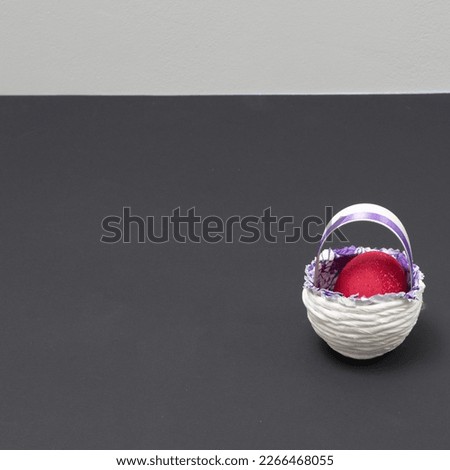 Easter scene with an egg in a basket on a black background. Minimal Easter composition.