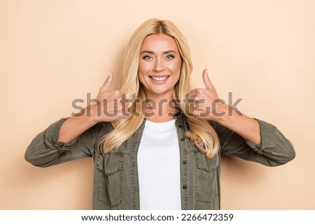 Photo of confident pretty woman wear khaki shirt showing two thumbs up isolated beige color background