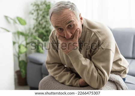 Frustrated unhappy middle aged mature man sitting on sofa, feeling depressed alone at home. Confused senior retired grandfather worrying about difficult life decision, copy space, old people solitude Royalty-Free Stock Photo #2266475307