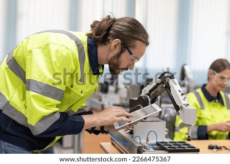Male engineer using remote testing and control AI robot model in academy robotics automation laboratory room for use in manufacturing or industry