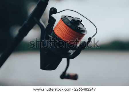 Close up shot of a fishing reel with orange braided line Royalty-Free Stock Photo #2266482247