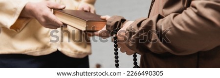 Cropped view of muslim father giving book to son with prayer beads at home, banner Royalty-Free Stock Photo #2266490305