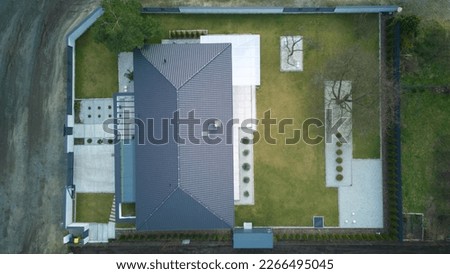 Top down aerial view of a private modern house with grey tiled roof and spacious yard with modern garden.