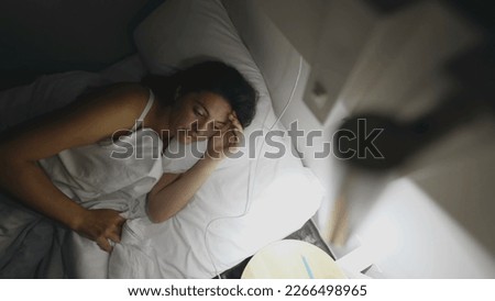 Woman turning bedside light ON in the middle of the night. Female person getting up early in the morning before sunrise Royalty-Free Stock Photo #2266498965