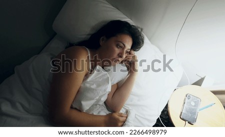 Woman laying in bed at night unable to sleep. Person turning light on in the middle of the night suffering from insomnia feeling stress with ruminating thoughts Royalty-Free Stock Photo #2266498979