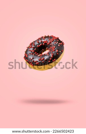 Delicious donut with chocolate icing isolated on pink background. Modern food concept. Advertising for pastry shops, cafes.