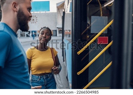 Multiracial young friends entering the bus on a station. Diverse tourists in new town. Best friends traveling together in a city. Focus on a young african american woman. Copy space.